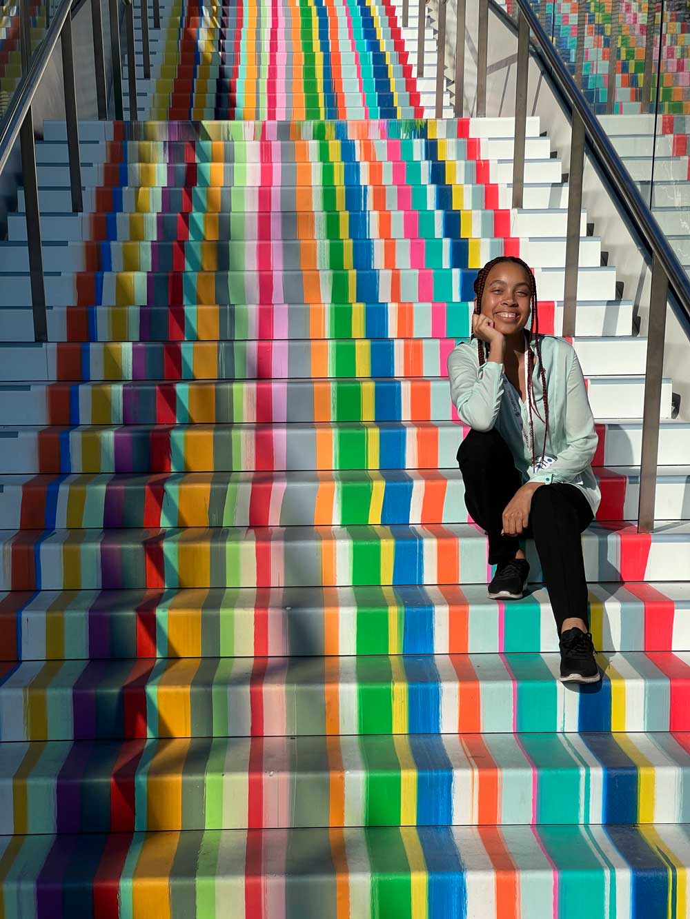 Kameron smiling and sitting on rainbow colored staircase